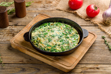 omelet with spinach, greenery and cheese on old wooden table