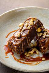 Brownie with caramel and nuts on brown plate macro close up vertical