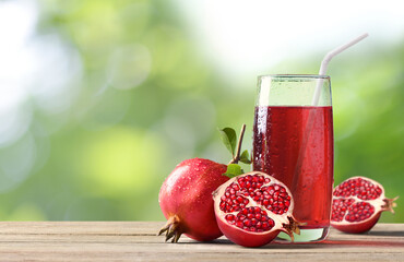 Pomegranate juice with fresh pomegranate fruits on wooden table.