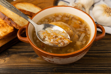 Buckwheat soup with carrots, potatoes and chicken on a brown wooden rustic table. Healthy food. Soup with croutons, garlic and spices. Copy space.
