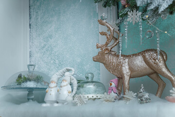 Beautiful shiny reindeer toy with gnomes and snowflakes on frozen window background. Merry...