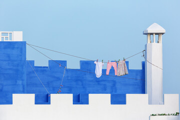 Clothesline with laundry drying outside blue and white stone house. - 518961068