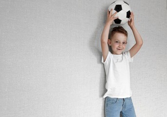 boy holding soccer ball in his hands, boy in a white t-shirt holding soccer ball in his hands on a...