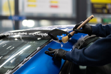 car detailing workshop, male working with brush, cleaning car body