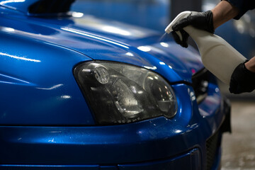 male detailer doing work on the car, cleaning machine and applying spray on the surface