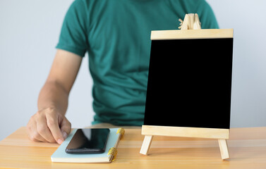 small black board on wooden table,blank blackboard isolated and man with smartphone