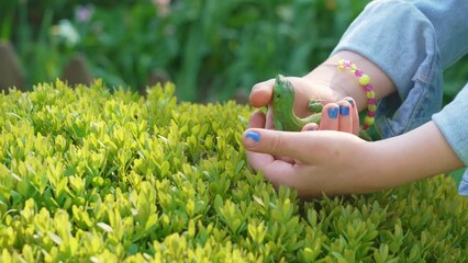 a little girl holding a small green lizard in her hands. lizards catch beetles, butterflies and other crop pests, feed on bears, which helps gardeners and farmers. an unusual pet. 