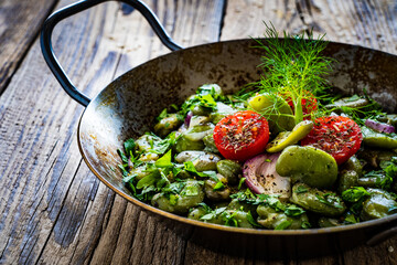 Broad beans with cherry tomatoes, garlic, toasted bread and parsley in cooking pan on wooden table
 - obrazy, fototapety, plakaty
