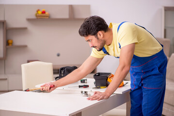 Fototapeta premium Young male carpenter repairing table at home