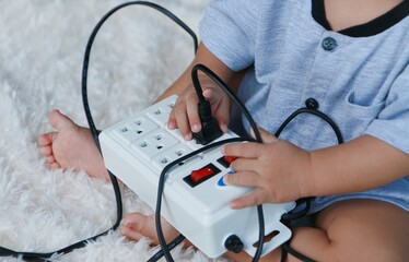 A 1-year-old boy is curiously playing with an electric socket. under the concept of safety care for...