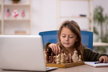 Young little girl playing chess at home