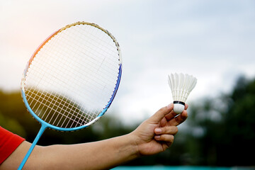 Hand holds shuttlecock for playing badminton outdoors.   Concept : Sport with equipment, workout....