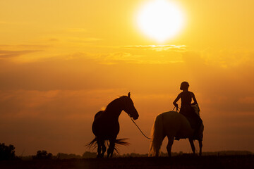 Fototapeta na wymiar silhouette of a woman riding a horse and the other is on a rope