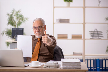 Old male employee working at workplace