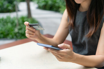 Closeup of Asian businesswoman using mobile phone while holding credit card, Female shopping online or booking ticket. Business, technology and lifestyle concept.