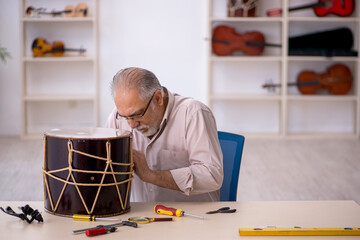 Fototapeta na wymiar Old male repairman repairing musical instruments at workshop