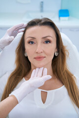 Woman face being examined by a medical worker with both hands