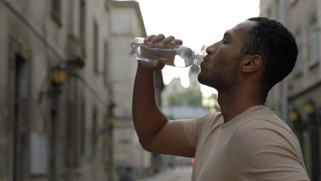 Side view of the man runner drinking water after the scamper. Man feels thirsty and drinks water after running. Sport and healthy lifestyle concept.
