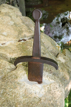 sword set in the stone in the middle of the forest of trees symbol of the legend of King Arthur