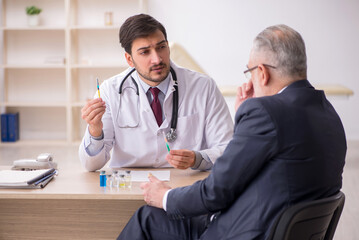 Old businessman visiting young male doctor in vaccination concep