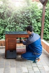 Handsome repairman fixing wooden furniture outside on the backyard