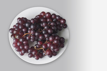 top view a bunch of purple grapes placed on a white dish on grey background, fruit, copy space