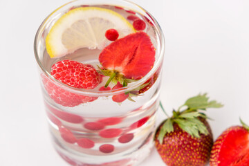 Summer refreshing cocktail with strawberries, berries, lemon and ice, side view.