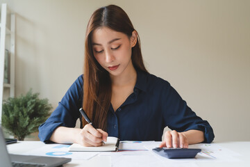 Women business people use calculators to calculate the company budget and income reports on the desk in the office.