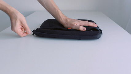 Man hand putting laptop into a case, zipping it up and taking away of the table. Action. Close up...