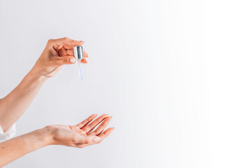 Hands of cropped white woman holding cosmetic serum pipette