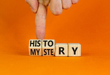 History versus mystery symbol. Concept words History and mystery on wooden cubes. Businessman hand. Beautiful orange table orange background. Business, History versus mystery concept. Copy space.