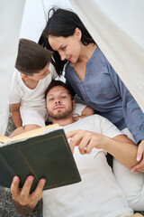 Family reading an evening fairy tale in cozy, magical hut