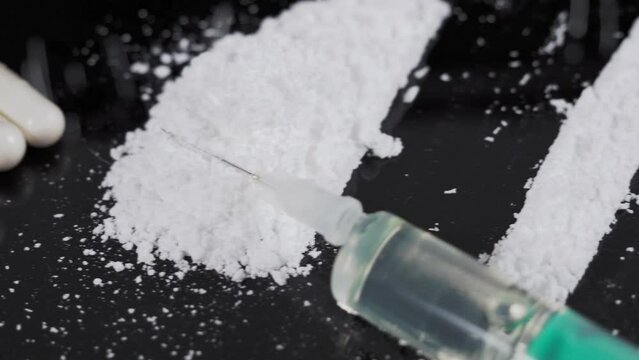 Money and drugs on a black glass table. Money, syringe and drugs.