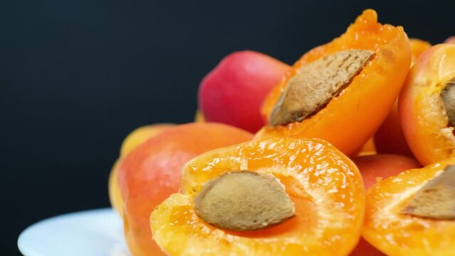 A lot of ripe juicy apricots in motion spin in a circle, peeled apricots with pits.
