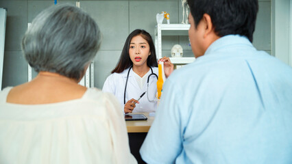 Female orthopedic doctor Explaining the precautions concerning knee and ligaments to elderly female patients and her son listened in the diagnostic room.	