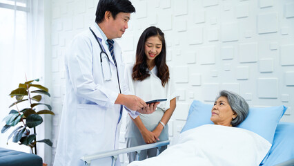 Obraz premium Specialist male doctor describing the improving symptoms of an elderly female patient. Elderly female patient smiling upon hearing better results from a male doctor.