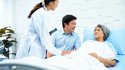 Obraz premium Female doctor enters patient room to tell a better outcome of treatment while elderly patients and her son was having fun chatting. Female patient and a son greet the doctor with bright smiles.