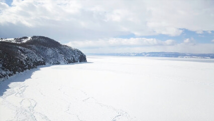 Baikal Lake in winter season, aerial view. Clip. Flying over the rocks and hills near the shore of the frozen amazing water reservoir, the beauty of nature concept.