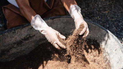 Close up hands of a farmer holding fertile soil and shoveling on the farm.
