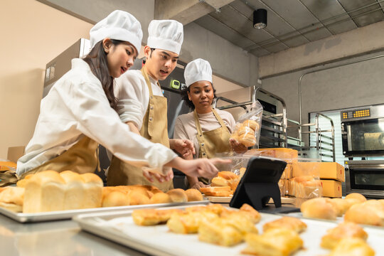 Young Asian and African American  chef startup partners, small business blogger live mobile application technology, bakery sales online promotion. at kitchen.Chef looking at the phone camera