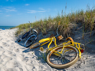 Two bikes laying on the sand dune at the entrance to the beach