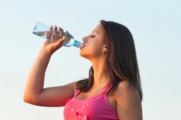 Young woman drinking water in summer