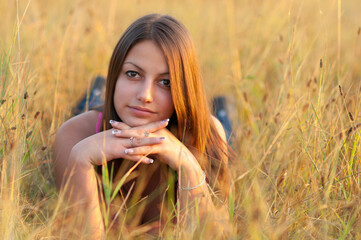 Young smiling woman lying in the grass on a sunny summer day