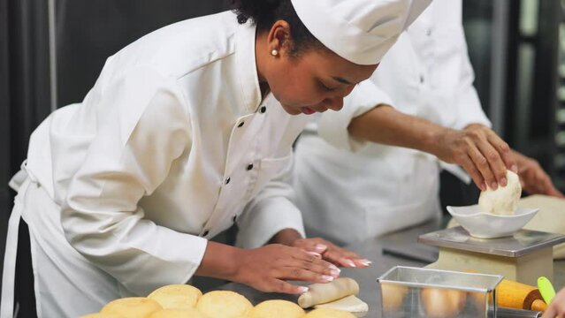 Smiling african  female bakers looking at camera.Chefs  baker in a chef dress and hat, cooking together in kitchen.Professional cooks in uniform preparing meals for a restaurant.