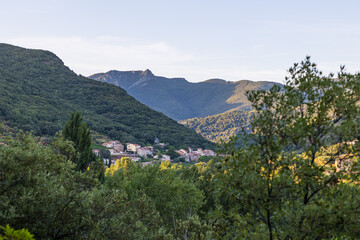 Fototapeta na wymiar Vue au coucher du soleil sur le hameau de Ceps, sa forêt, son vignoble et les montagnes du Parc naturel régional du Haut-Languedoc