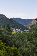 Fototapeta premium Vue au coucher du soleil sur le hameau de Ceps, sa forêt, son vignoble et les montagnes du Parc naturel régional du Haut-Languedoc