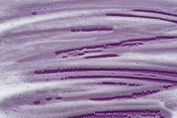 Fototapeta na wymiar Foam swatch on a violet background. Soapy liquid texture with bubbles. Natural sunshine and shadows. Skin care cleansing cosmetic in top view.