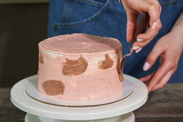 female hands add chocolate decorations to the pink cake. birthday cake