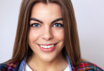 Naklejka premium Studio portrait of happy young woman in plaid shirt posing against wall.