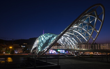 Bridge of Peace bow-shaped pedestrian bridge in Old Tbilisi town the Capital of Georgia. Twilight evening lights shot.